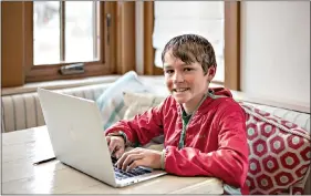  ?? Renie/Jackson Hole News & Guide via AP) ?? Charlie von MaurNewcom­b, 11, smiles at his home April 15 in Kelly, Wyoming, as he writes stories for his online newspaper, “Kelly Out Loud!” (Kayla