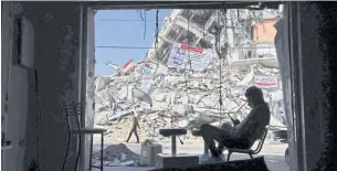  ?? AFP ?? A man sits in a damaged shop at a building that was partially by Israeli air strikes in Gaza City.