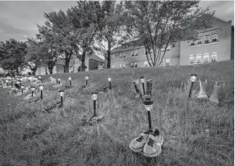  ?? REUTERS ?? Pairs of children’s shoes and toys are seen at memorial in front of the former Kamloops Indian Residentia­l School after the remains of 215 children, some as young as three years old, were found at the site, in Kamloops, B.C.