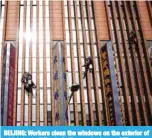  ?? — AFP ?? BEIJING: Workers clean the windows on the exterior of a highrise building in Beijing yesterday.