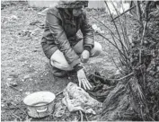  ?? ?? Iryna Abramova kneels to touch the clothing her husband was wearing before Russian soldiers destroyed their home, marched them outside at gunpoint and executed him.