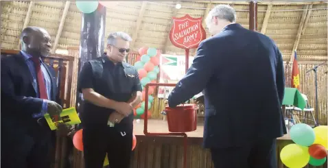  ??  ?? Rod Henson, Country Manager of ExxonMobil Guyana making his first contributi­on during the launch of the Salvation Army Guyana Division annual Christmas kettle appeal as Foreign Secretary of the Ministry of Foreign Affairs Carl Greenidge and Roraima Airways Chief Executive Officer Captain Gerry Gouveia looks on. (Photo by Terrence Thompson)