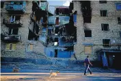  ?? NATACH PISARENKO/ASSOCIATED PRESS ?? A man walks with his dog near destroyed buildings in Gorenka on the outskirts of Kyiv, Ukraine, on Wednesday. Many more bodies are being found in Mariupol.