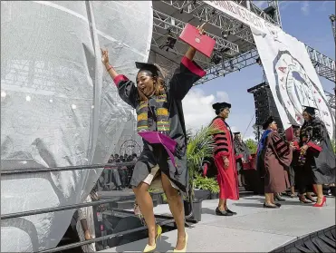  ??  ?? A jubilant Clark Atlanta University graduate high-steps into the future after receiving her degree during the school’s 30th annual commenceme­nt ceremony Monday in Atlanta.