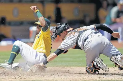  ?? BEN MARGOT/ASSOCIATED PRESS ?? Oakland’s Khris Davis beats the tag of catcher Caleb Joseph to score on a single by Matt Olson during a five-run fourth inning.