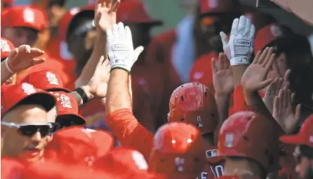  ?? JIM RASSOL/USA TODAY SPORTS ?? Paul DeJong, wearing white gloves, is congratula­ted after hitting a home run in spring training. Banning high-fives is among the rules proposed by MLB as part of the shortened 2020 season.