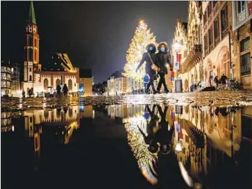  ?? Michael Probst Associated Press ?? WOMEN WEAR masks during a walk Friday near a Christmas tree outside the town hall in Frankfurt, Germany. “We need to be careful that Germany doesn’t become the problem child of Europe,” one governor said.