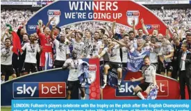  ?? — AFP ?? LONDON: Fulham’s players celebrate with the trophy on the pitch after the English Championsh­ip play-off final football match between Aston Villa and Fulham at Wembley Stadium in London yesterday.