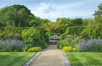  ??  ?? Roses, nepeta and irises flank the path leading to a Lutyens-designed bench