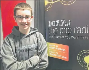  ?? JEREMY FRASER/CAPE BRETON POST ?? Adam MacLean stands near a banner in his bedroom promoting his radio station. The New Waterford native launched an online classic rock radio station last week and has already received positive feedback from listeners. MacLean is only 15 years old.