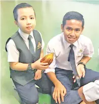  ??  ?? ANIQ Aqil dan rakan karibnya Mohd Syafik menimba pengalaman pertama memegang buah koko.