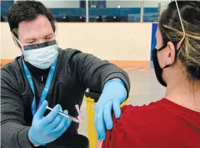  ?? STEVE SOMERVILLE TORSTAR FILE PHOTO ?? A paramedic receives her vaccine in York Region. With the vaccine in play and a post-pandemic world on the horizon, no shortcuts can be taken, write Shawn Rosemarie and Andrew Miller.