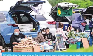  ?? — AFP ?? SHENYANG, China: This photo taken on May 15, 2022 shows people selling items from the trunks of their cars along a river in Shenyang, in China’s northeaste­rn Liaoning province.