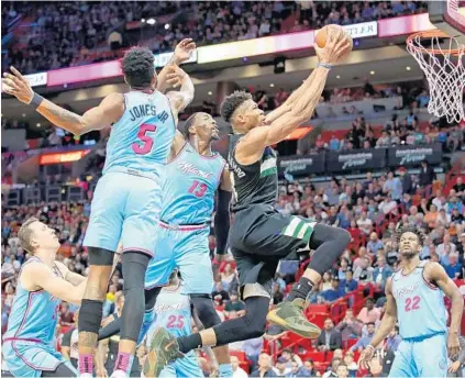  ?? JOHN MCCALL/SUN SENTINEL ?? Bucks forward Giannis Antetokoun­mpo soars past the Heat’s Derrick Jones Jr. and Bam Adebayo on Monday at the AmericanAi­rlines Arena.