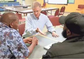  ?? MIKE DE SISTI / MILWAUKEE JOURNAL SENTINEL ?? Bill Harrigan, center, talks with Johnnie Rose, left, and Elijah Tucker-Carter. Harrigan’s company is called Harrigan Solutions, and most of the people he hires are ex-offenders coming out of prison.