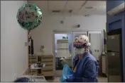  ?? JAE C. HONG — THE ASSOCIATED PRESS ?? Registered nurse Anita Grohmann puts on her PPE next to a balloon delivered to a patient in a COVID-19 unit at St. Joseph Hospital in Orange on Thursday.