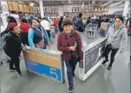  ??  ?? Varios clientes de una tienda en Ciudad de México cargan televisore­s que adquiridos en un menor precio por el programa de El Buen Fin