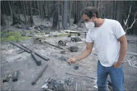  ??  ?? JANE TYSKA — BAY AREA NEWS GROUP Satchel MacLennan finds his brass guitar slide on his family’s property in Last Chance. The CZU Lightning Complex Fire destroyed 1,490 structures, including his parent’s home and the cabin he grew up in.