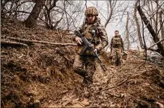  ?? Tyler Hicks / The New York Times ?? Ukrainian soldiers walk through a trench position Saturday outside Toretsk, in the Donetsk province of eastern Ukraine. Ukraine insisted that its forces were fending off relentless Russian attacks in Bakhmut.