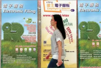  ?? PROVIDED TO CHINA DAILY ?? A pedestrian walks past an advertisem­ent billboard for paying tax by electronic means in the Central district of Hong Kong.