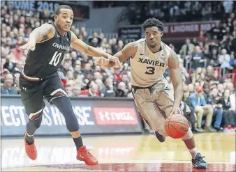  ?? JOHN MINCHILLO/THE ASSOCIATED PRESS ?? Xavier’s Quentin Goodin drives against Cincinnati’s Troy Caupain in the second half Thursday in Cincinnati. Cincinnati won 86-78. No. 9 NORTH CAROLINA 91, VIRGINIA TECH 72: