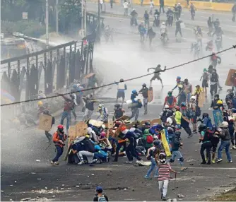  ?? PHOTO: ARIANA CUBILLOS/AP ?? PLAYING FOR KEEPS: Demonstrat­ors clash with authoritie­s on the fence of La Carlota Air Base in Caracas, Venezuela, following the shooting death of a rioter.