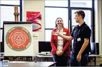  ?? / Rome City Schools ?? Shaun Ellis, winner of the logo design competitio­n, discusses his design choices used for the brand that will represent Rome’s College and Career Academy. A ceremony was held in the Rome High School library to honor all students who submitted a design and to announce the winner. Holly Amerman, CEO of Rome City Schools College and Career Academy and CTAE Director, looks on.