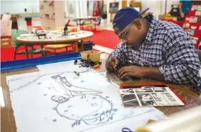  ?? STAFF PHOTO BY DOUG STRICKLAND ?? Malcolm Robinson uses resources on the fourth floor of the Chattanoog­a Public Library while designing a T-shirt for a client last Friday.