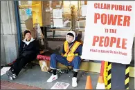  ??  ?? Cedar Sklar-Lures (center), sits chained to a doorway while protesting with his father, Leonard Sklar, outside of a Pacific Gas & Electric building in San
Francisco on Dec 16. (AP)