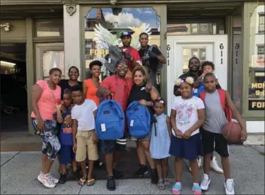  ?? NICHOLAS BUONANNO — NBUONANNO@TROYRECORD.COM ?? Employees of Foreva Fly Cuts Barbershop on 2nd Avenue in Troy, along with community members, display backpacks that were given away on Tuesday.