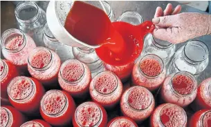  ?? KATHERINE FREY/THE WASHINGTON POST ?? David Holcomb fills quart-size jars with tomato juice.