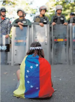  ?? REUTERS ?? Una niña frente a los guardias que impiden el paso a la morgue