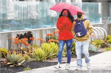  ?? K.C. ALFRED U-T ?? Alyssa Lopez and her fiancé, Tye Garcia, walk in the rain along the Pacific Beach boardwalk on a cold, windy afternoon Monday. The temperatur­e hit 58 at San Diego Internatio­nal Airport — a reading that was 7 degrees below average.