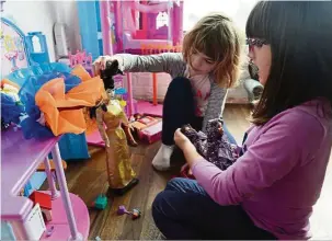  ??  ?? Five-year-olds Lucy Michaels (left) and Grace Fetterman play with dolls, including two wearing Hello Hijab.
