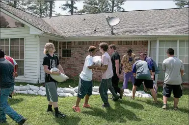  ?? Staff photo by Jerry Habraken ?? Members of the Ashdown High School football team help sandbag the perimeter of Sandy Davis’ home on Little River 21 Tuesday afternoon.