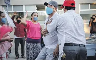  ??  ?? PASTOR Samuel Hernandez, right, assists Christian Acosta outside Tijuana General Hospital last week. Acosta, who has a cough and breathing problems, planned to seek treatment.