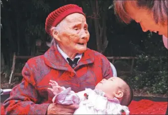  ?? WU CHUANMING / FOR CHINA DAILY ?? Zhu Zhengshi holds her sixth generation descendant at her 118th birthday party in Chengdu, Sichuan province, on Tuesday. Zhu was born in 1900 and gave birth to five children. She is hale and hearty and lives a regular lifestyle.