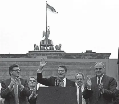  ?? IRA SCHWARTZ/AP ?? President Ronald Reagan acknowledg­es the crowd after his speech in front of the Brandenbur­g Gate in West Berlin on June 12, 1987, where he said, “Mr. Gorbachev, tear down this wall!”