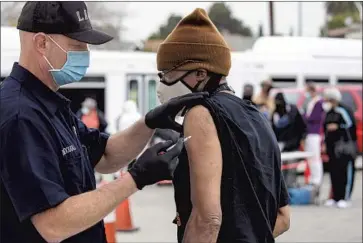  ?? IRFAN KHAN Los Angeles Times ?? FIREFIGHTE­R Anthony MacDougall gives a COVID-19 vaccine to Lawrence Taylor in Los Angeles on Feb. 9.