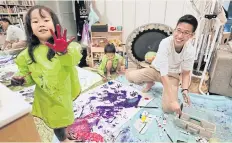  ??  ?? Kidsline babysitter Jun, right, paints with two children at their home in Tokyo.