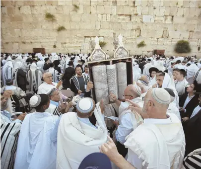  ?? AP FILE PHOTO ?? HONORING: Israelis hold a Torah scroll prior to the Cohanim Priestly caste blessing during the Jewish holiday of Passover, in front of the Western Wall, the holiest site where Jews can pray in Jerusalem's old city, last year.