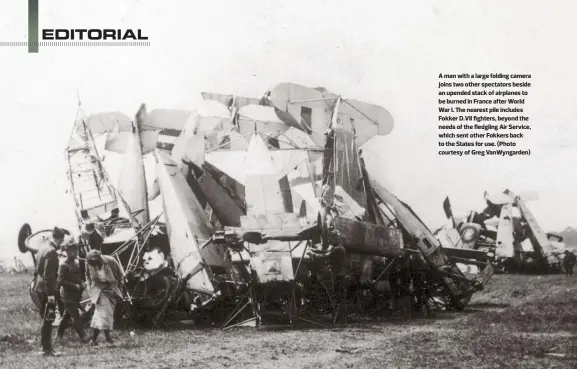  ??  ?? A man with a large folding camera joins two other spectators beside an upended stack of airplanes to be burned in France after World War I. The nearest pile includes Fokker D.VII fighters, beyond the needs of the fledgling Air Service, which sent other...