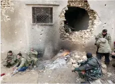  ?? — Reuters ?? Rebel fighters rest near a hole in the wall by a fire on the outskirts of the northern Syrian town of Al Bab, Syria.