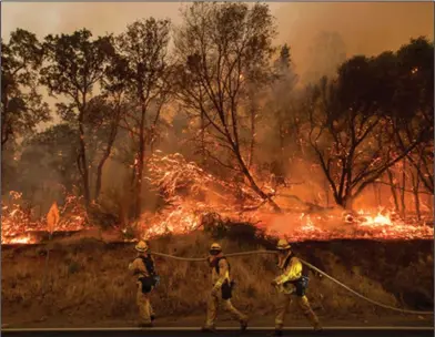  ?? Noah Berger/AP ?? Out of control: Firefighte­rs battle a wildfire as it threatens to jump a street near Oroville, Calif., on Saturday, July 8. Evening winds drove the fire through several neighborho­ods leveling homes in its path. Wildfires barreled across the baking landscape of the western U.S. and Canada, destroying a smattering of homes, forcing thousands to flee and temporaril­y trapping children and counselors at a California campground. Southern California crews hope slightly cooler temperatur­es and diminishin­g winds will help in the battle Sunday.