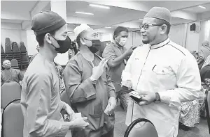  ?? — Gambar Bernama ?? BANTUAN: Muhammad Iqbal(kiri) menerima bantuan kewangan daripada Ahmad Marzuk (kanan) sempena Program Lambaian Kaabah di Dewan Haji Nik Abdullah Arshad, Kompleks Purnama di Pengkalan Chepa, Kota Bharu, semalam.