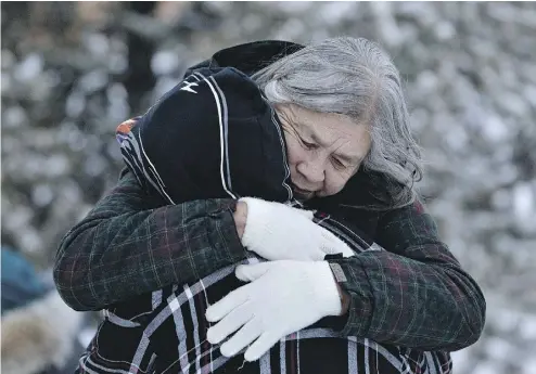  ?? JASON FRANSON / THE CANADIAN PRESS ?? Residents console each other at the memorial near the La Loche Community School in La Loche, Sask., Sunday. Four people were killed in a shooting Friday in the remote town, already plagued by mental illness, addiction and suicide.