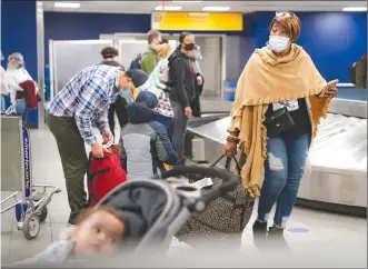  ?? Associated Press photo ?? Travellers wearing protective masks to prevent the spread of COVID-19 prepare to leave the Terminal C baggage claim area at LaGuardia Airport, Wednesday in the Queens borough of New York.