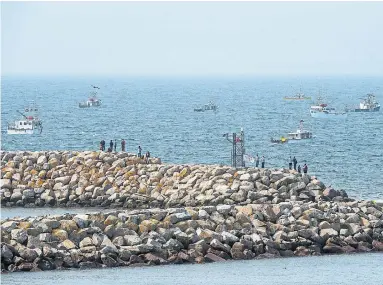  ?? ANDREW VAUGHAN THE CANADIAN PRESS FILE PHOTO ?? Members of the Sipekne’katik First Nation, the second-largest Mi’kmaq band in Nova Scotia, stand on the breakwater in Saulniervi­lle, N.S., as non-Indigenous boats protest the launch of a Mi’kmaq self-regulated fishery.