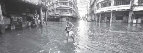  ?? FILE PHOTO ?? A woman crosses a flooded street in downtown Cebu City. The Task Force Gubat sa Baha vows to take advantage of the El Niño to fix the drainage system of the city.