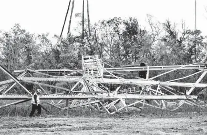  ?? Annie Flanagan / New York Times ?? Linemen work on a transmissi­on tower that fell during Hurricane Ida on a river crossing on Sept. 6 in Orleans Parish, La. Much of the state, including New Orleans, lost power for days because many of Entergy’s electrical poles and towers were outdated.